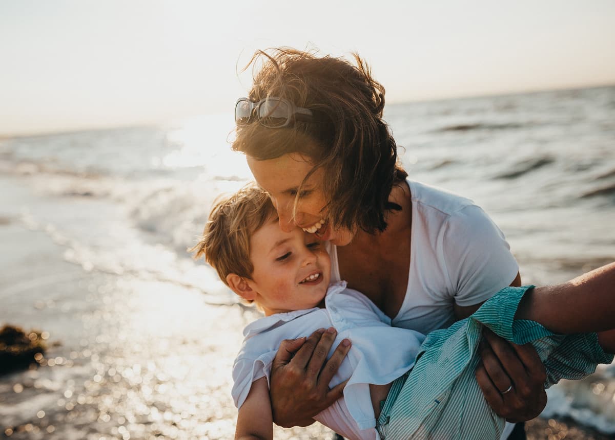 Woman smiling and holding a child at the beach